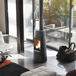 Modern freestanding wood-burning fireplace beside floor-to-ceiling windows in a contemporary living room.