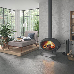 Modern living room with suspended wood-burning fireplace beside floor-to-ceiling windows and concrete flooring.