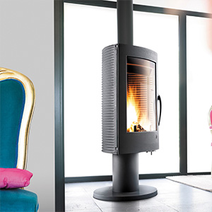 Contemporary cylindrical wood-burning stove with panoramic glass window in modern minimalist interior.